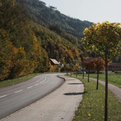A picturesque rural road winding through autumn foliage in Eisenerz, Austria.
